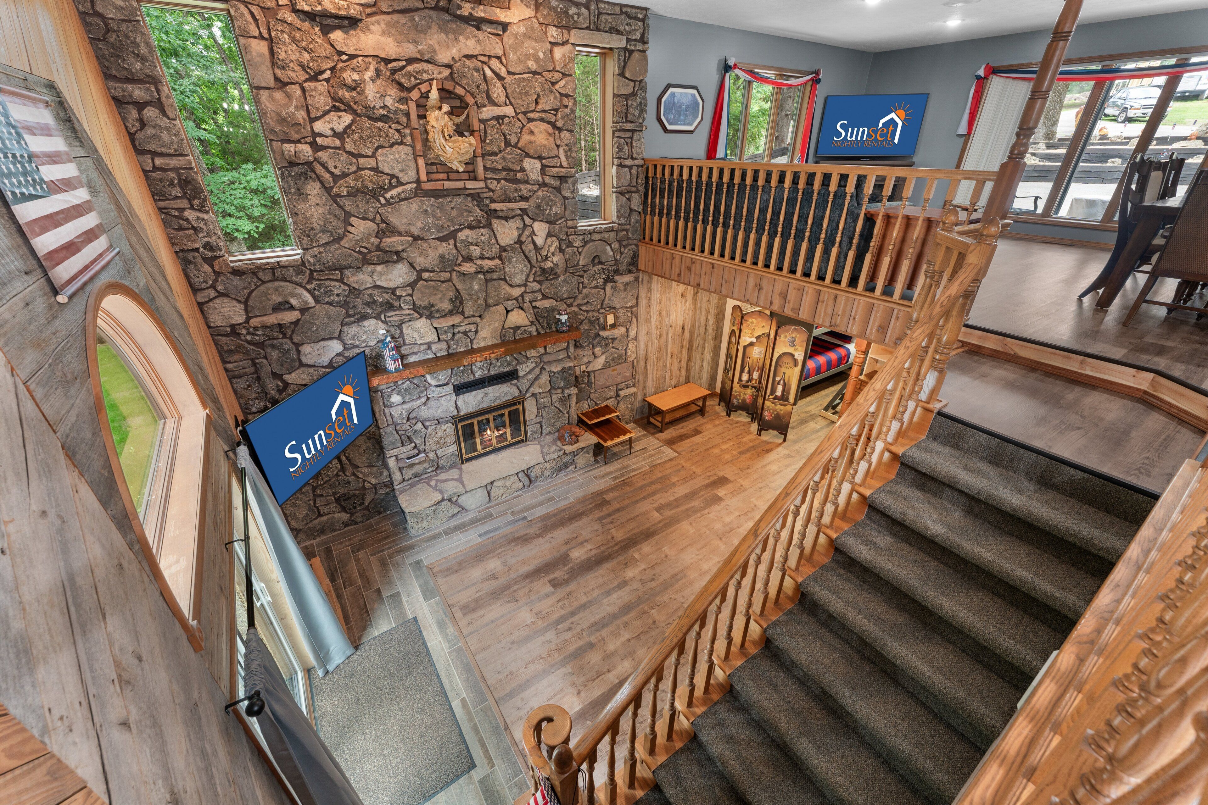 A hotel interior with a stone fireplace, wooden staircase, and a sign indicating the direction to the Sunset Inn.