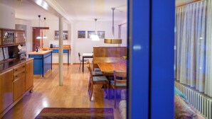 A modern kitchen with wooden cabinets, a dining area with a table and chairs, and a view through a glass door. - Steinröschen, (Flumserberg Tannenboden), by Interhome (Flumserberg Tannenheim)