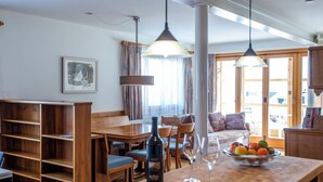 A dining area with a wooden table, chairs, a wine bottle, and wine glasses. - Steinröschen, (Flumserberg Tannenboden), by Interhome (Flumserberg Tannenheim)