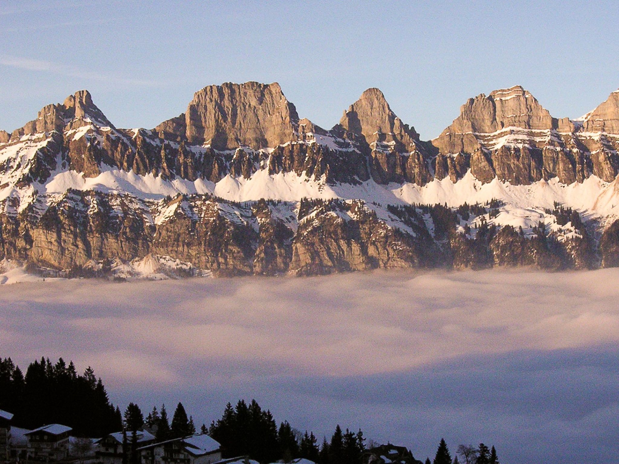 A mountain range with snow-covered peaks and a valley below.