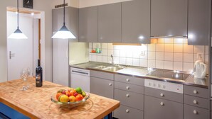 A modern kitchen with grey cabinets, a wooden countertop, a bowl of fruit, a wine bottle, and pendant lighting. - Steinröschen, (Flumserberg Tannenboden), by Interhome (Flumserberg Tannenheim)