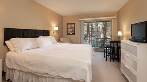 Une chambre avec un lit, une télévision, un bureau avec des chaises et un balcon avec vue.