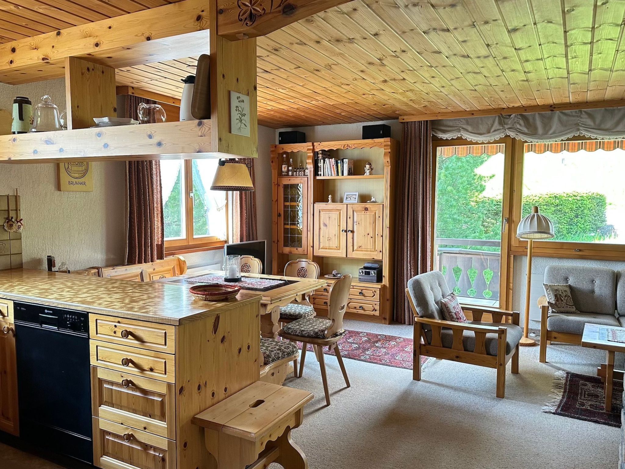 Ein gemütliches Blockhaus-Interieur mit einer Holzküche, Essbereich und Sitzgelegenheit.