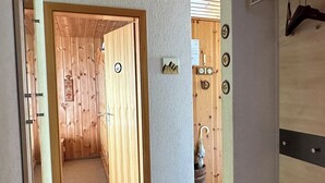 A wooden door leading to a room with a wooden ceiling and a small clock on the wall.