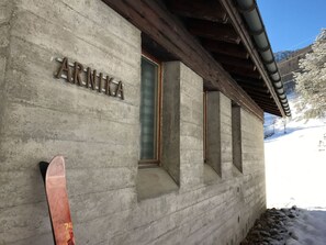 Een gebouw met de naam 'ARNIKA' op de gevel, een houten dak en een met sneeuw bedekte grond.