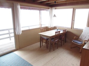 Un espace repas comprenant une table et des chaises, de grandes fenêtres et un plafond en bois.