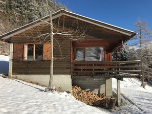 Une cabane en bois dotée d’un balcon, entourée d’arbres couverts de neige.