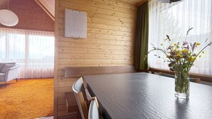 A wooden interior with a dining table, chairs, a vase with flowers, and a bulletin board. - Haus DOMO, (Flumserberg Tannenboden), by Interhome (Mols)
