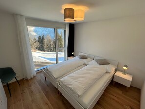 A modern bedroom with a large bed, a view of a snowy landscape, and a sliding glass door.