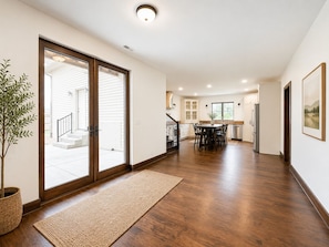 Un intérieur spacieux avec un plancher en bois, un coin repas et une cuisine dotée de meubles blancs.