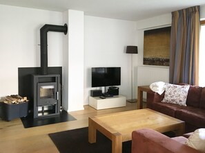 Una sala de estar con chimenea, televisor, sofá y mesa de centro.