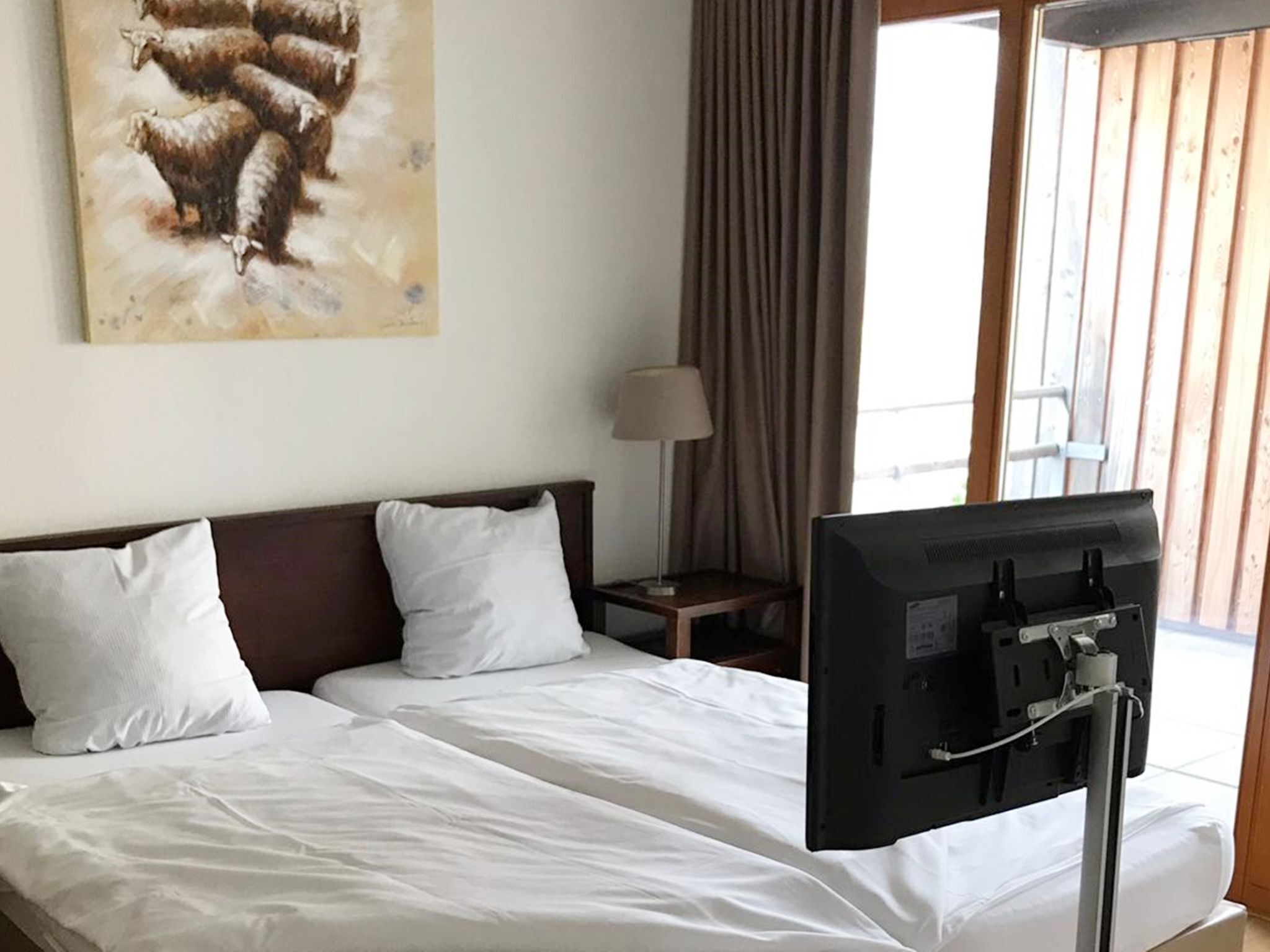 Une chambre d’hôtel avec un lit, une télévision, une lampe et un tableau au mur.