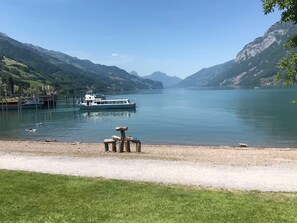 Un lago tranquilo con un bote amarrado al muelle, rodeado de montañas.
