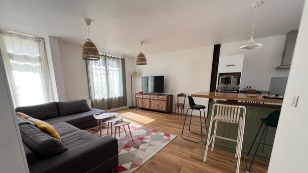Ett modernt vardagsrum med soffa, matplats, kök och tv.
