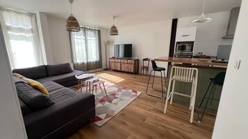 Un espace de vie moderne comprenant un canapé, un coin repas, une cuisine et un téléviseur.