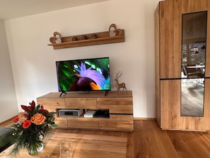 Eine Holzunterhaltungseinheit mit einem Flachbildfernseher, einem dekorativen Hirsch und einer Blumenkomposition.