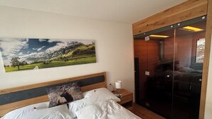 A hotel room with a bed, a nightstand, a lamp, a wooden headboard, a large landscape painting, and a sliding door.