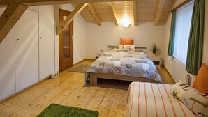 A bedroom with a wooden ceiling, a bed with a quilt, a nightstand, a window with curtains, and a door. - Casa Riposo, (Flumserberg Tannenheim), by Interhome (Flumserberg Tannenheim)