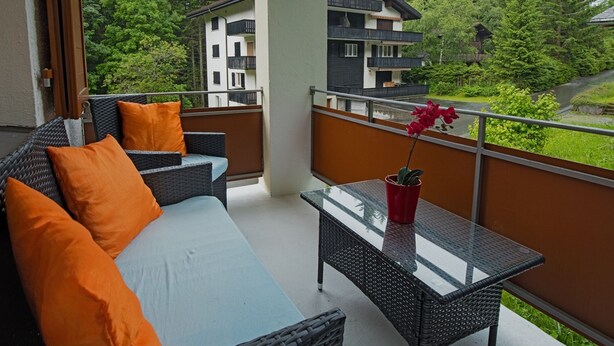 A balcony with wicker furniture, a glass table, and a potted plant. - Casa Riposo, (Flumserberg Tannenheim), by Interhome (Flumserberg Tannenheim)