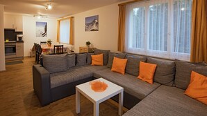 A modern living room with a sectional sofa, a dining area, and a kitchen. - Casa Riposo, (Flumserberg Tannenheim), by Interhome (Flumserberg Tannenheim)