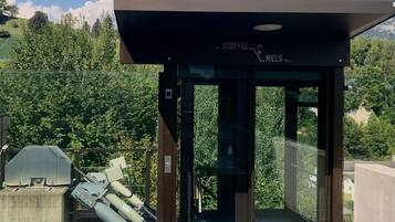 A modern building entrance with a glass door and a sign indicating 'STOFFEL MELS' at 535m elevation.