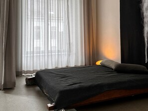 A room with a bed, a window with sheer curtains, and a wall-mounted light. - Design Loft - Herrschaftlich, (Mels), by Interhome (Mels)