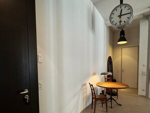 A room with a wooden dining table, two chairs, a wall-mounted clock, and a door with a key lock. - Design Loft - Herrschaftlich, (Mels), by Interhome (Mels)