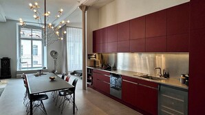 Una cocina moderna con armarios rojos, una campana extractora de acero inoxidable y un comedor con mesa y sillas.