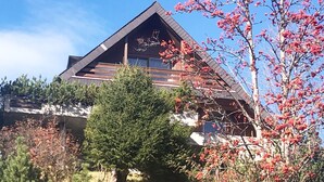 A modern building with a triangular roof, surrounded by trees and shrubs. - Haus DOMO, (Flumserberg Tannenboden), by Interhome (Mols)