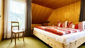 A wooden room with a bed, a chair, and a window. - Haus DOMO, (Flumserberg Tannenboden), by Interhome (Mols)