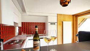 A modern kitchen with a wine bottle and glasses on the counter. - Haus DOMO, (Flumserberg Tannenboden), by Interhome (Mols)