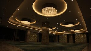 Un intérieur spacieux avec un espace central ouvert, de nombreux lustres et un motif décoratif sur les murs.