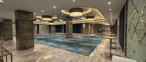 A spacious lobby with a central area, columns, and a patterned floor.