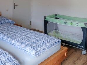A bedroom with a single bed, a crib, and a door. - Dachwohnung Tannenboden, Whg. Schmid, (Flumserberg Tannenboden), by Interhome (Flumserberg Tannenheim)