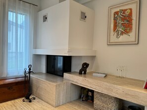 A modern kitchen with a built-in oven, a dining area with a marble countertop, and a framed artwork on the wall.