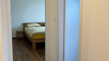 Ein Schlafzimmer mit einem hölzernen Bett, einem Nachttisch und einer Tür zu einem anderen Raum.