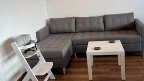 Una sala de estar moderna con un sofá seccional gris, un sillón blanco y una pequeña mesa blanca.