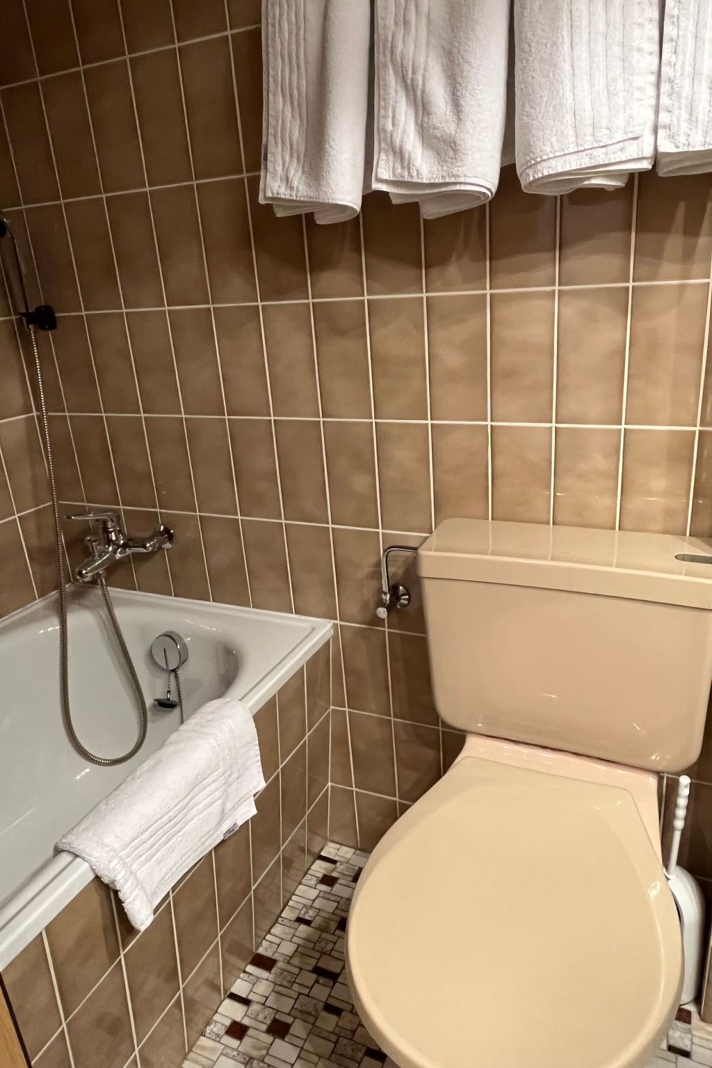A bathroom with a bathtub, toilet, and tiled walls.
