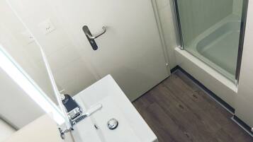 Une salle de bain avec un lavabo blanc, des toilettes et une douche à parois de verre.