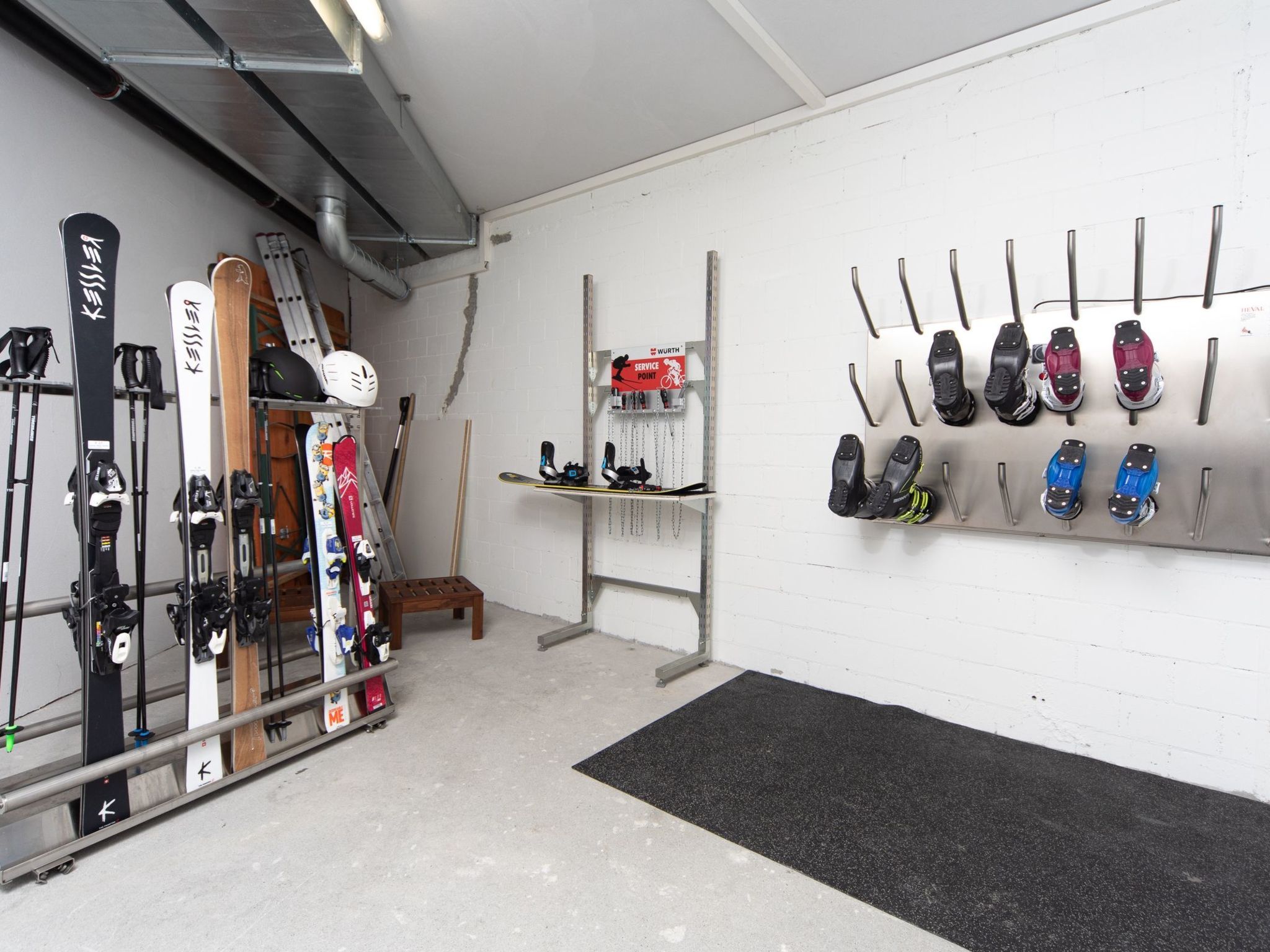 A ski equipment storage area with skis, poles, and boots organized on racks and shelves.