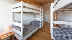 Een slaapkamer met stapelbed, houten plafond, nachtkastje met lamp en een garderobe.
