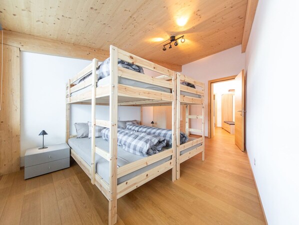 A bunk bed room with a desk and a lamp.