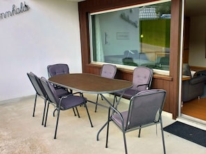 A conference room with a round table and four chairs, a large window, and a view of the outside.