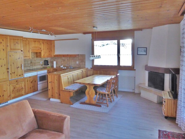 A kitchen with wooden cabinets, a dining table with chairs, a built-in oven, and a fireplace.
