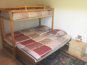 A bunk bed with a lower bunk, a bedside table, and a small dresser.