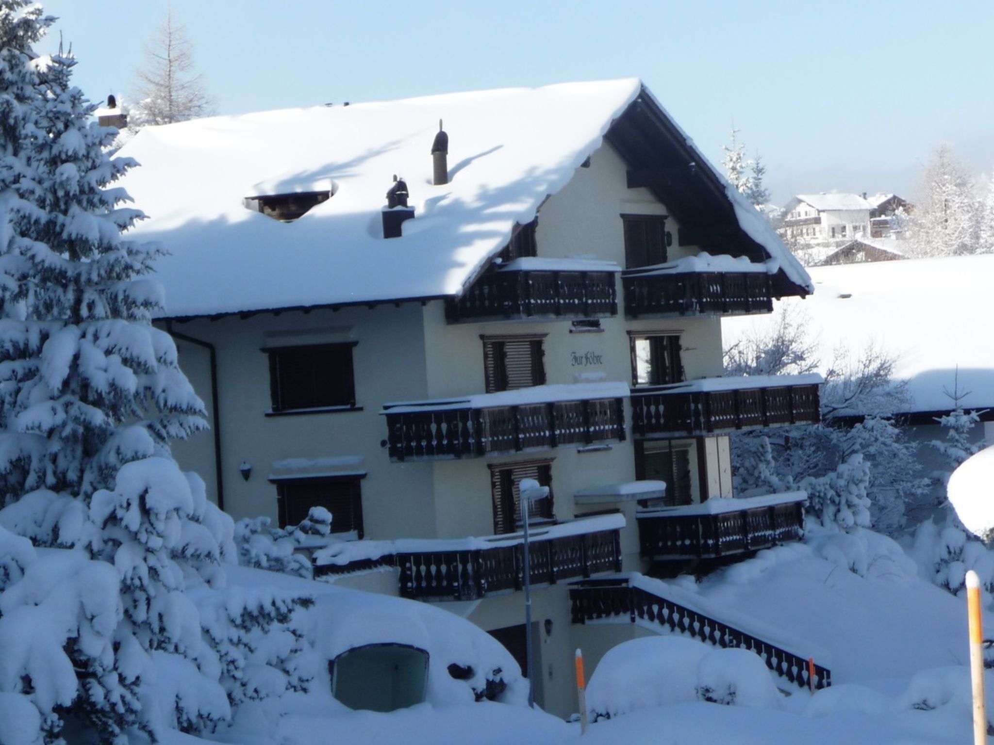 A multi-story building with balconies, surrounded by snow-covered trees.