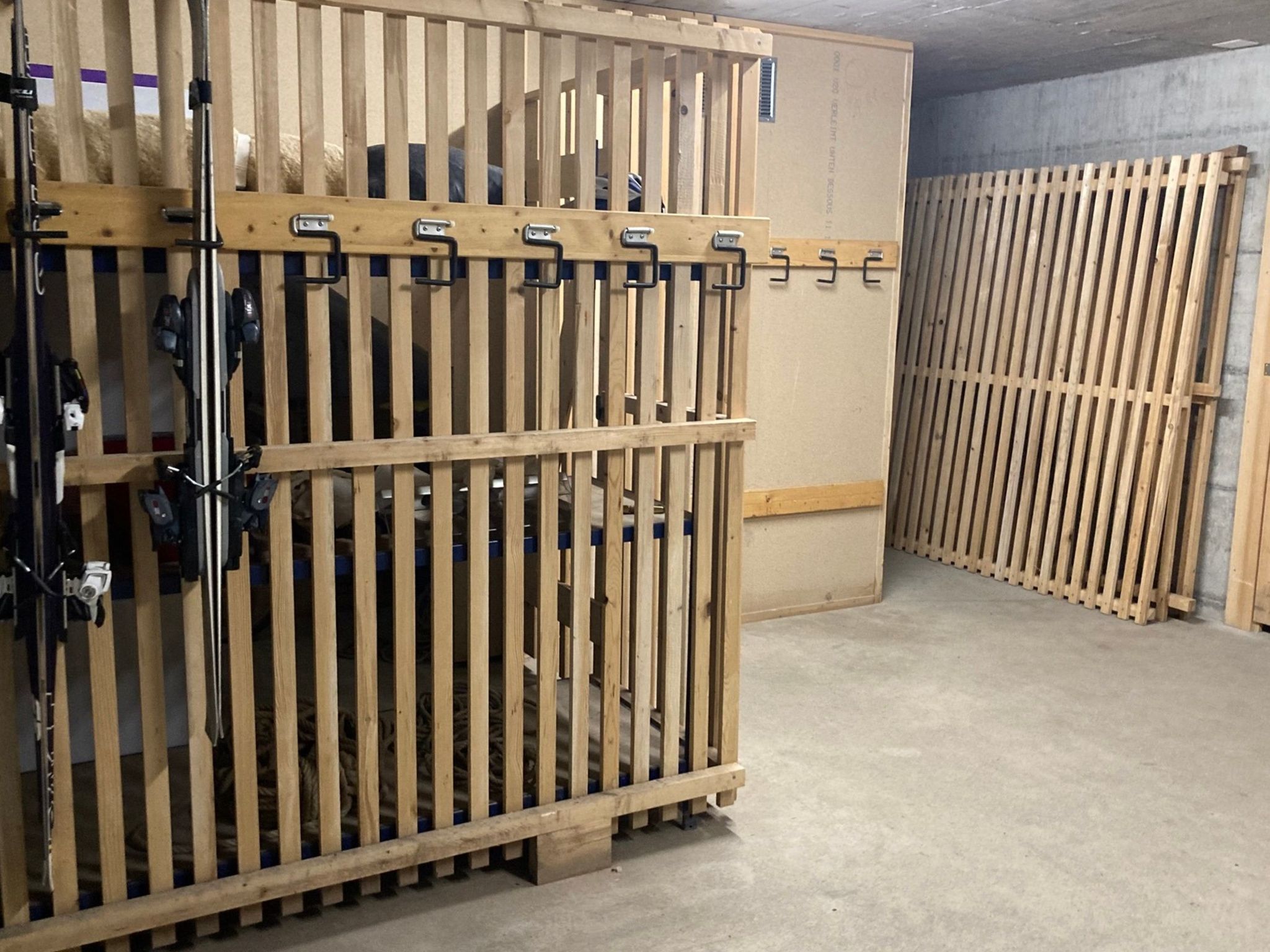 A storage area with wooden racks and metal hooks.