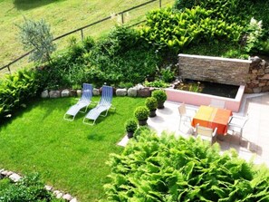 A backyard with a stone wall, a small pond, and two lounge chairs.