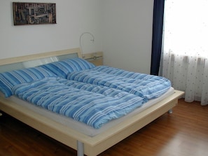 A single bed with a wooden frame and a headboard, a bedside table, and a wall-mounted artwork. - Egglisboden, (Quarten), by Interhome (Mols)