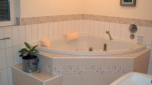 A bathroom with a freestanding bathtub, a sink, and a potted plant.